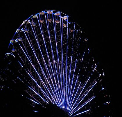 A beautiful Giant Wheel with blue lights at night.