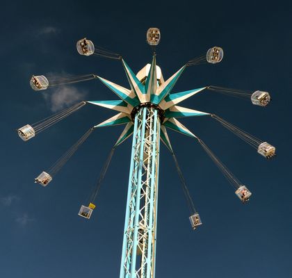 A tall swinger ride with many seats hanging at a height.